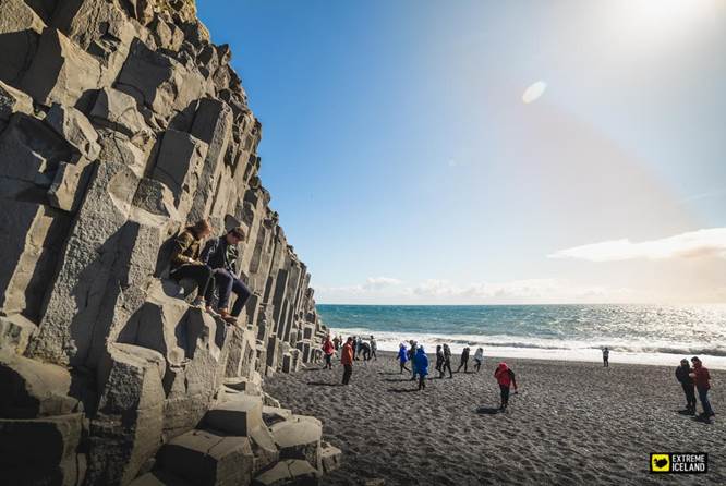 游客在黑沙滩玄武岩石柱旁