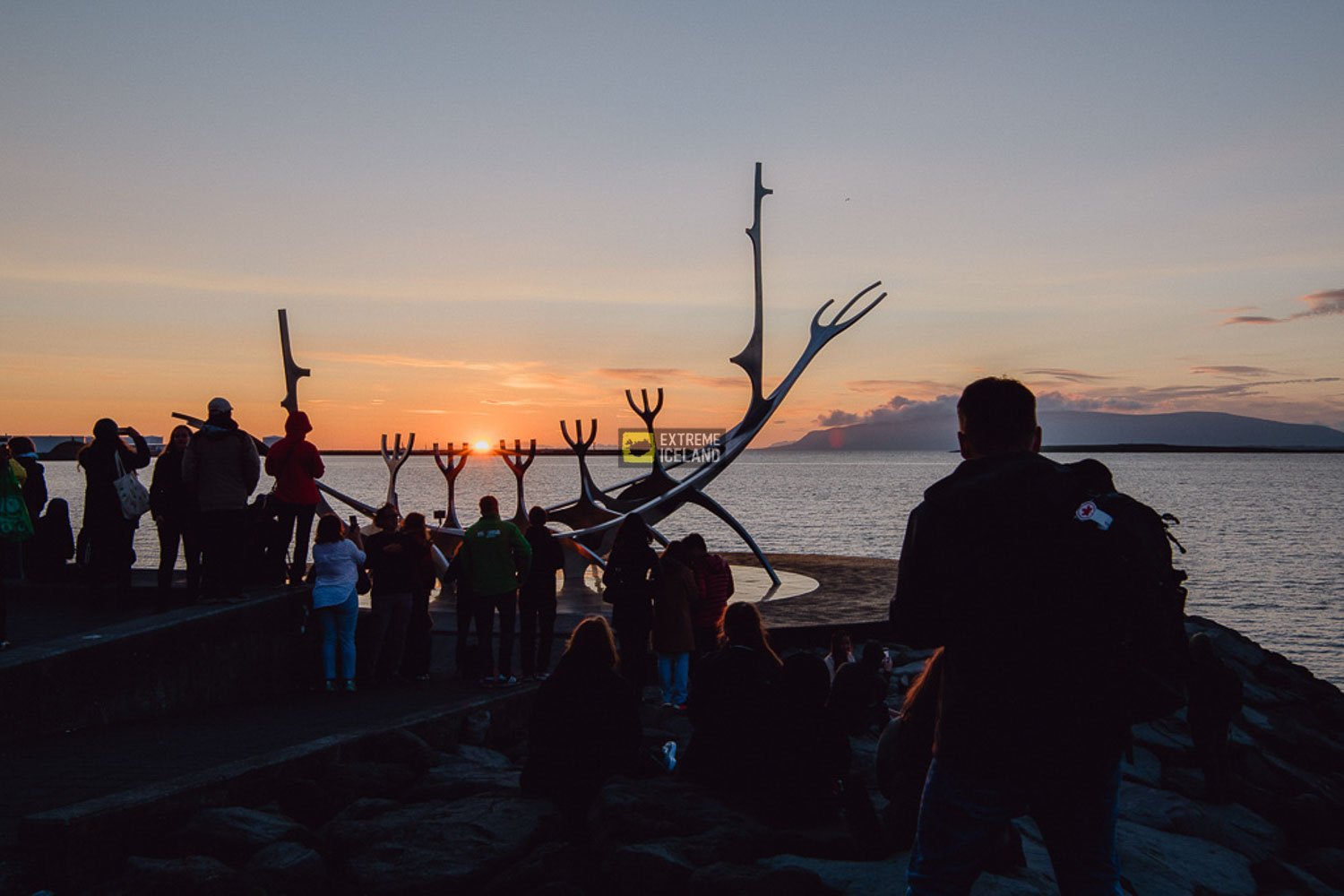 夏至日在雷克雅未克海岸线太阳航行者雕塑旁看日落的人